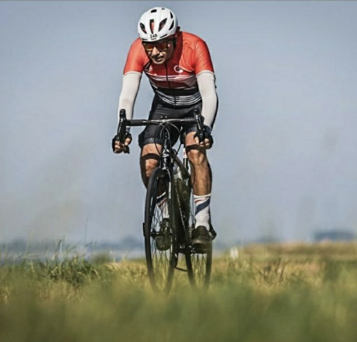 My dad on his bike, mid-race, riding through tall grass under an open sky