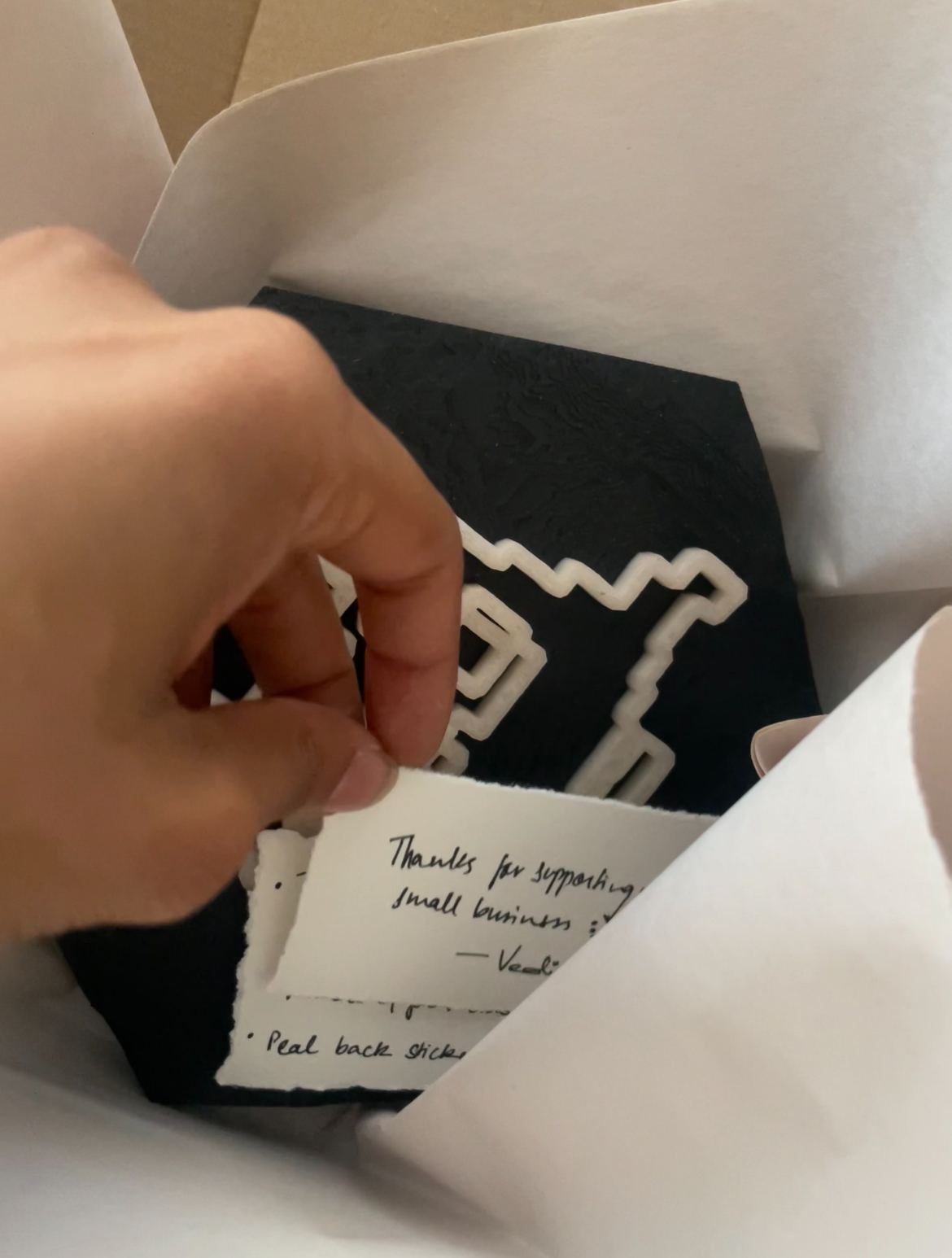 A 3D printed terrain trophy hexagon packed in tissue with a handwritten thank-you note